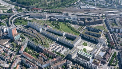 Luftaufnahme von städtischem Gebiet mit Gebäuden und Bahnstrecken.