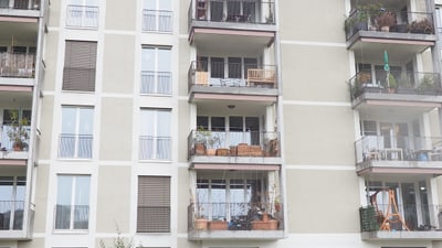 Mehrfamilienhaus mit Balkonen und begrüntem Vordergrund.