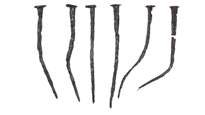 Antike, rostige Nägel nebeneinander auf weissem Hintergrund.