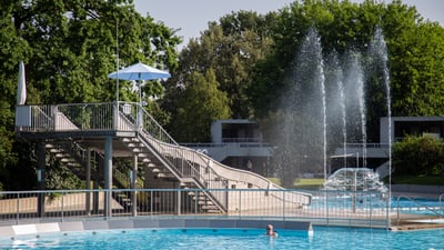 Schwimmbad mit Rutsche und Fontänen.