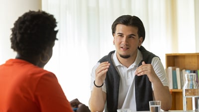 Gespräch zwischen zwei Personen am Tisch.