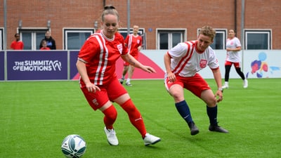Frauenfussballspiel auf grünem Rasen mit roten Trikots.