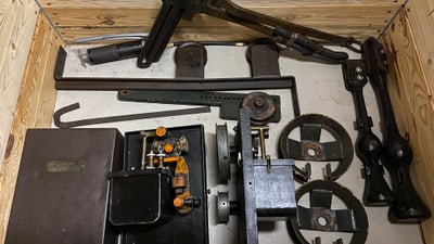 Alte Maschinenteile in einer Holzkiste.