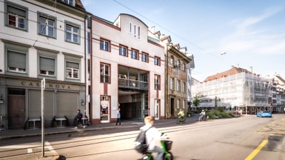Strassenszene mit Gebäuden und einer Person auf einem Roller.