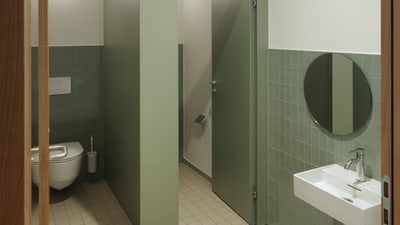 Öffentliche Toilette mit Kabine, Waschbecken und Spiegel.
