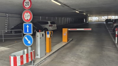 Einfahrt in ein Parkhaus mit Schranke und Verkehrsschildern.