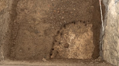 Ausgrabungsstätte mit Erd- und Steinschichten.