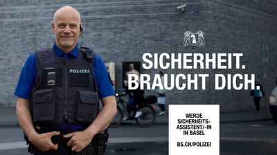 Polizist in Uniform steht vor gemauerter Wand.
