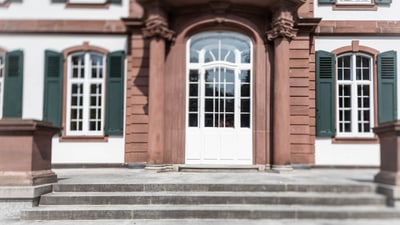 Blick auf eine Fensterfront und eine Steintreppe vor einer Glastür