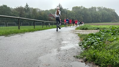 Gruppe von Joggern auf einem nassen Weg im Freien.