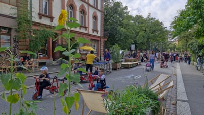 Kinder fahren Dreirad auf verkehrsberuhigter Strasse in der Stadt.