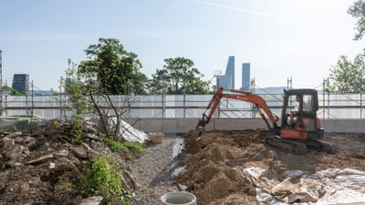 Baustelle mit Bagger und Skyline im Hintergrund.