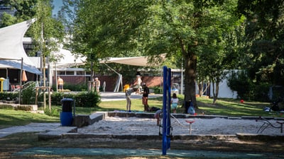 Spielplatz mit Menschen vor einem Gebäude im Freien.