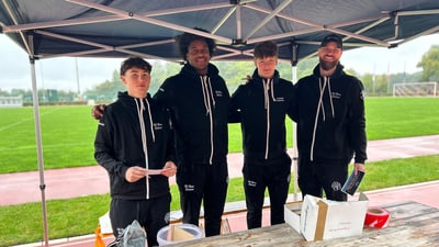 Vier Spieler des Basketballclubs Bären unter Zelt auf Sportplatz bei Regen.