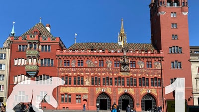 Rathaus Basel mit Fresken und Turm bei blauem Himmel.