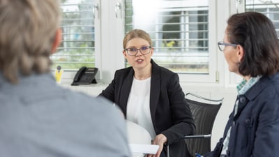 Frau in Geschäftsgespräch mit zwei Personen.