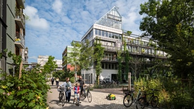 Moderne Wohnsiedlung mit Fahrradfahrern und Bäumen.
