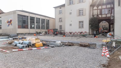 Baustelle mit Bauausrüstung vor Gebäuden im Sonnenlicht.