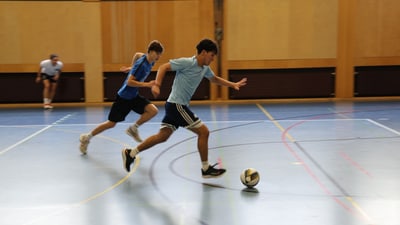 Zwei Männer spielen Hallenfussball in der Turnhalle.