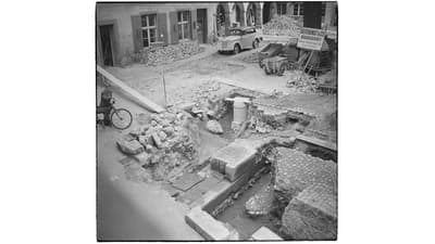 Baustelle in einer städtischen Strasse mit Ausgrabungen und Fahrzeugen im Hintergrund.