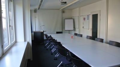 Moderner Konferenzraum mit Tisch und Stühlen.
