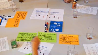 Menschen sitzen an einem Tisch mit Notizen und Getränken.