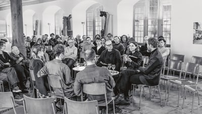 Menschen sitzen in einem Raum und hören einem Vortrag zu.