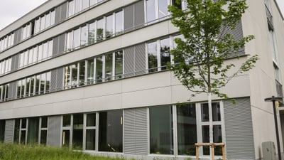 Moderne Gebäudefassade mit Baum im Vordergrund.