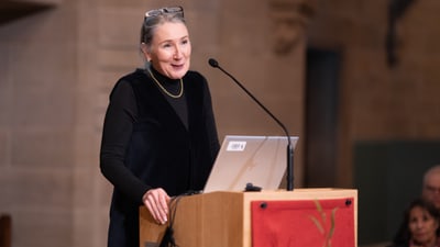 Frau hält eine Rede hinter einem Podium.