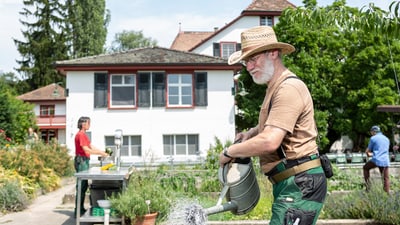 Drei Personen arbeiten im Garten des Vollzugszentrums.