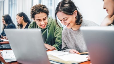 Gruppe von Studenten beim Lernen mit Laptops und Büchern.",