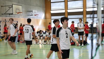 Jugendliche beim Volleyballspiel in einer Sporthalle.