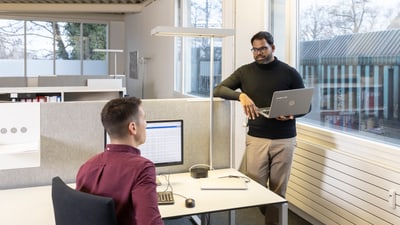 Zwei Männer unterhalten sich in einem modernen Büro.