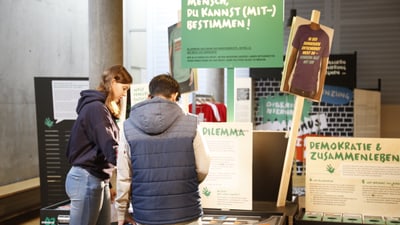 Zwei Jugendliche betrachten eine Ausstellung über Demokratie.