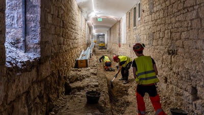 Arbeiter in einem Steinkorridor, die einen Graben ausheben.