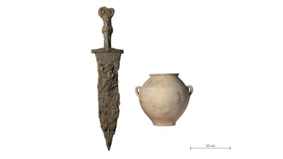 Antikes Schwert und Keramikgefäss auf weissem Hintergrund mit Massstab.