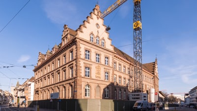 Historisches Gebäude mit Baukran auf sonniger Strasse.