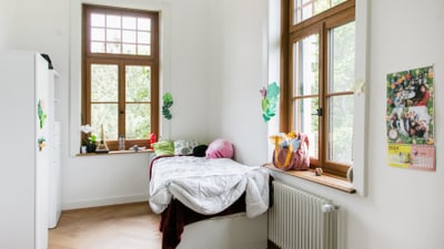 Helles Schlafzimmer mit Bett neben Fenster.