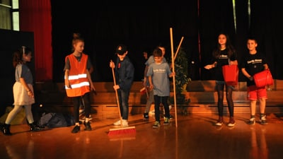 Kinder führen ein Theaterstück auf der Bühne auf.