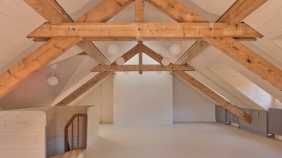 Heller Dachboden mit sichtbaren Holzbalken.