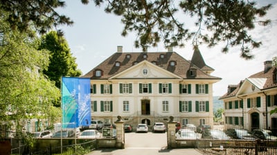 Historisches Gebäude mit einem blauen Banner und Autos davor.