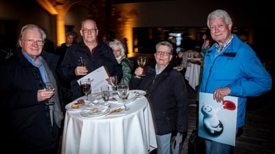 Gruppe älterer Menschen bei einem Stehempfang mit Getränken und Essen.