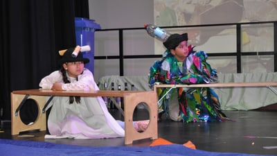 Kinder in Kostümen auf der Bühne bei Theateraufführung.",