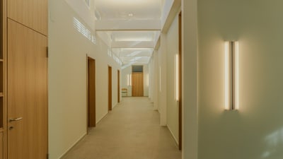 Langer Flur mit Holztüren und Wandleuchten.