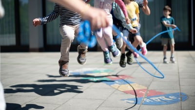 Kinder spielen Seilhüpfen.