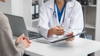 Arzt im Gespräch mit Patient am Schreibtisch.