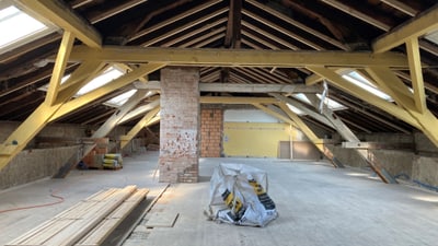 Dachboden mit Holzbalken und Baumaterialien.