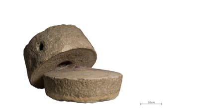 Zwei alte Mühlsteine auf weissem Hintergrund mit Massstab 10cm