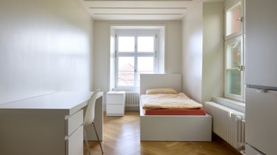 Helles, minimalistisches Schlafzimmer mit Schreibtisch und Bett.