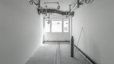 Leerer Raum mit Kabeln an der Decke und Fenstern am Ende.